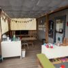 Überdachte Terrasse des Bauwagens mit Spielmaterial, Tischen und Bänken